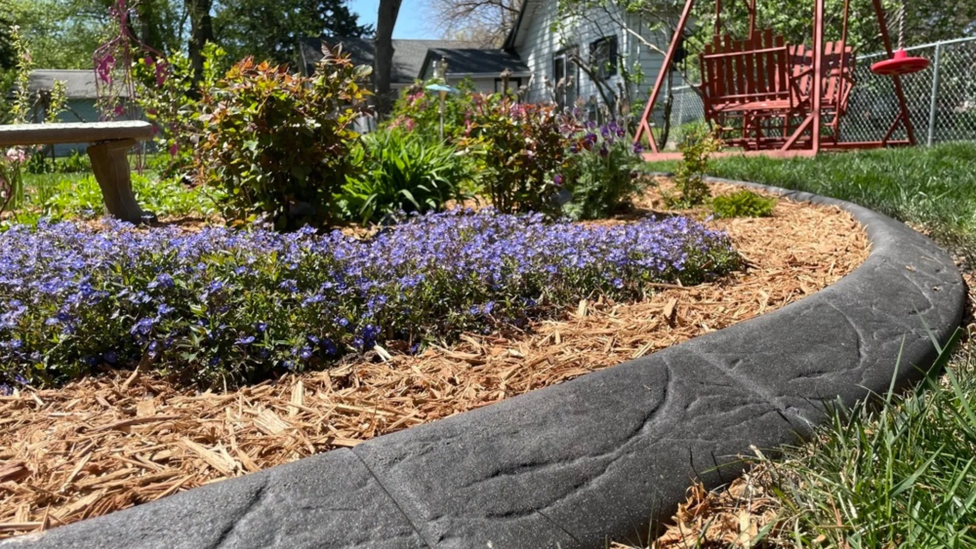 Garden landscape featuring flowers and a stamped concrete border in Waukee, IA.