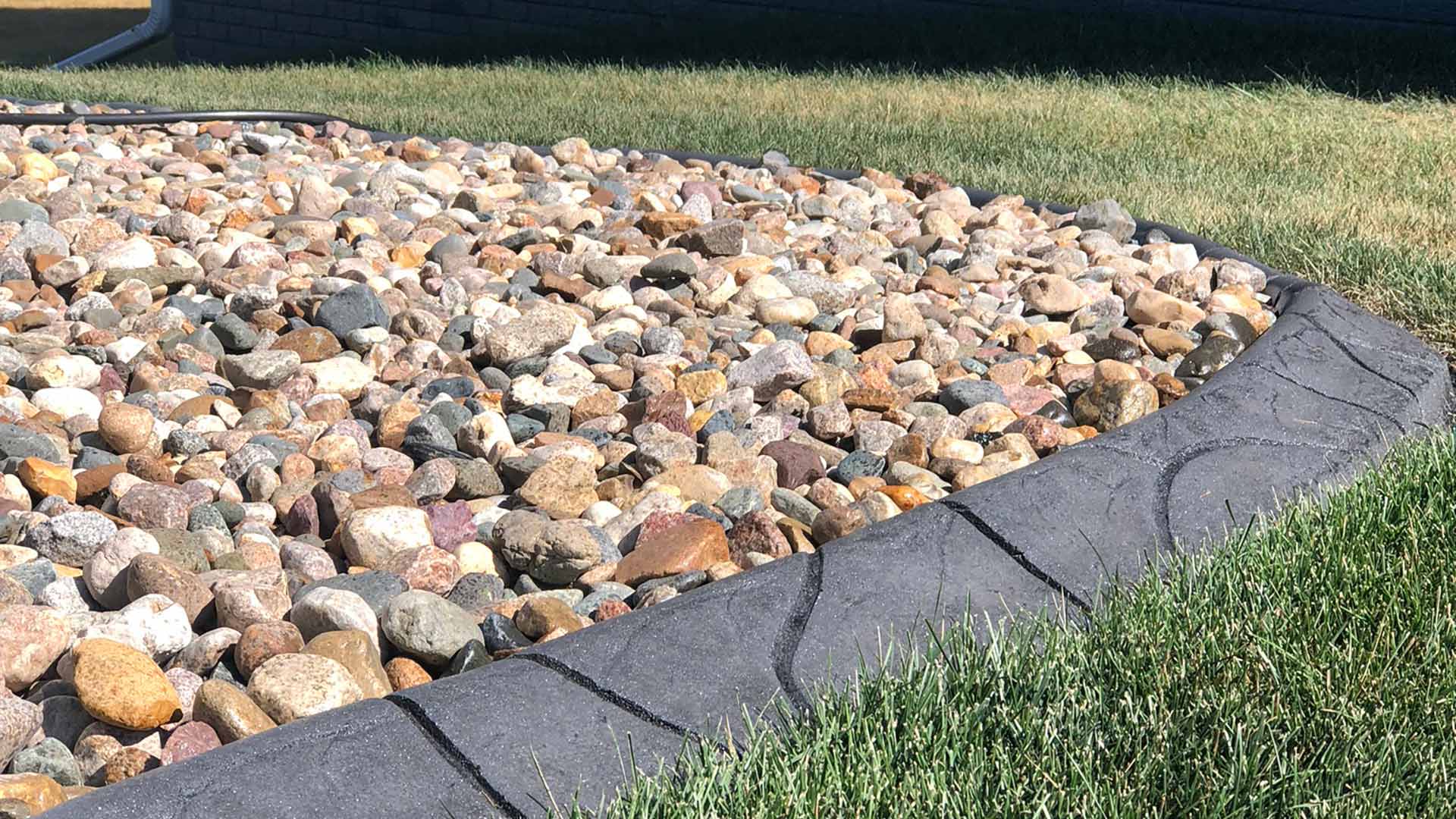 Concrete edging border installed by rock bed in Waukee, IA.