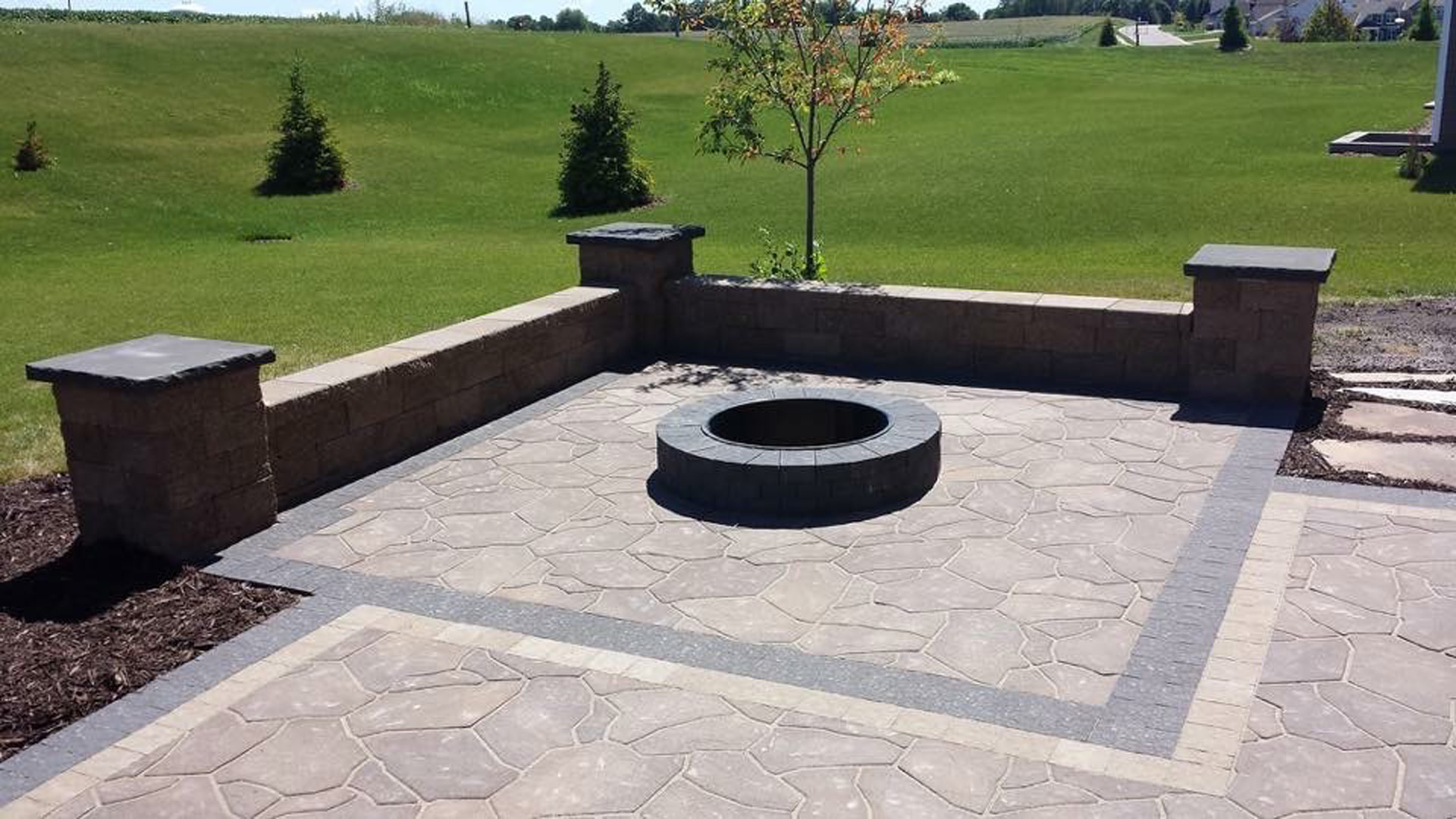 Fire pit, patio, and seating wall installed for landscape in Johnston, IA.