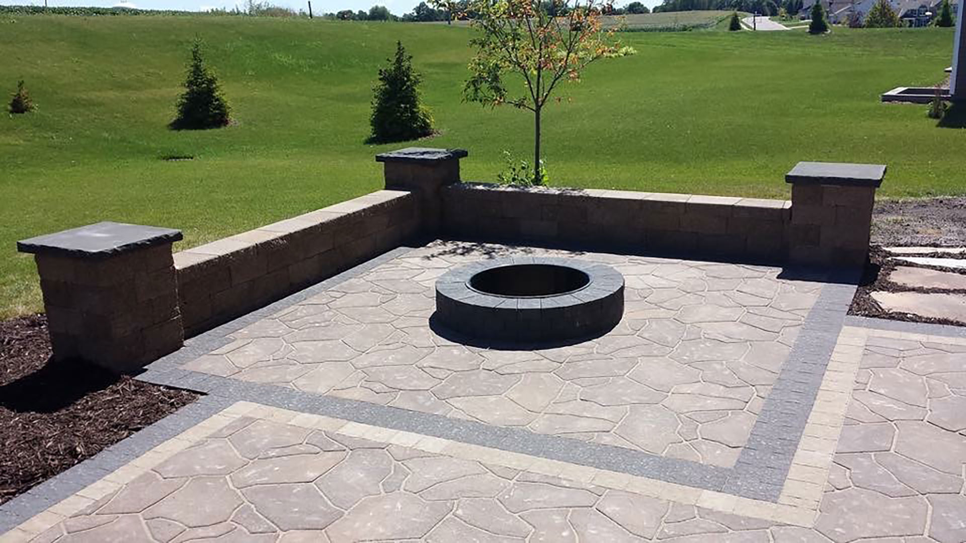 Hardscape features installed including seating wall, patio, and fire pit in Urbandale, IA.
