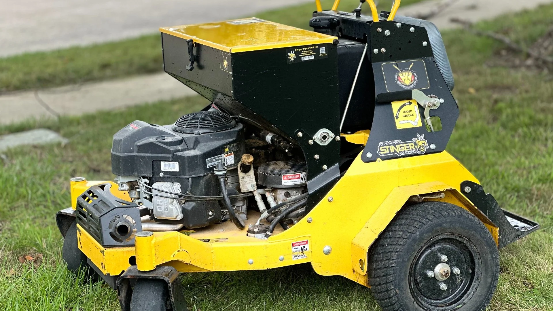 Yellow lawn aerator parked on grass for maintenance.