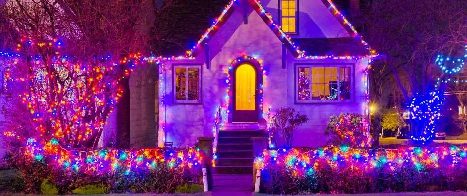 Colored Christmas lights on a house, trees, and shrubs in Waukee, IA.
