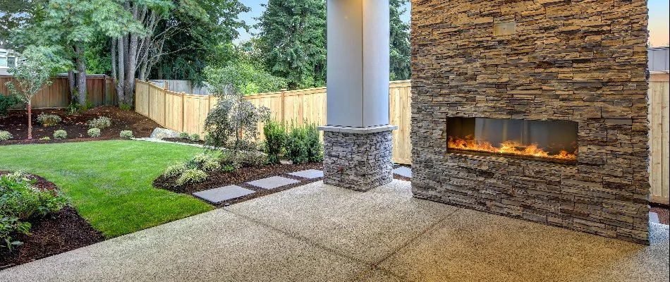 Lawn and fence in Waukee, IA, by an outdoor fireplace.
