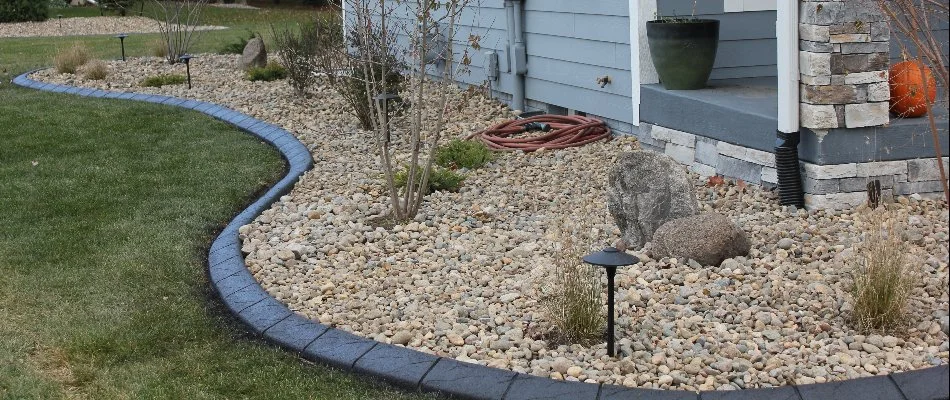 Lamps with LED bulbs in Waukee, IA, located within a landscape bed with rock ground cover. 