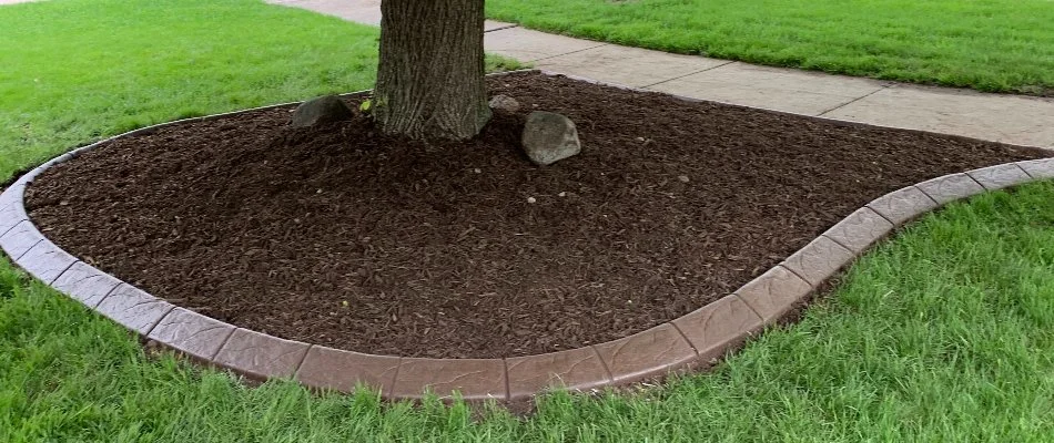 Mulch ground cover on a landscape in Waukee, IA, by a lawn.