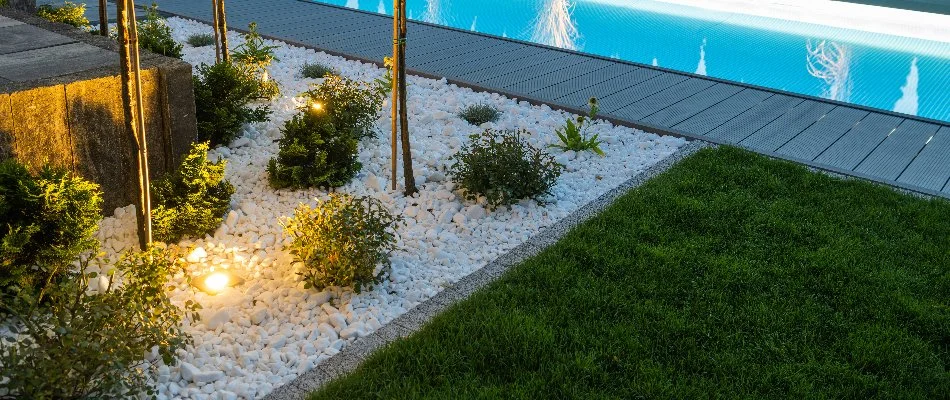 Poolside landscaping with outdoor lighting in Waukee, IA.