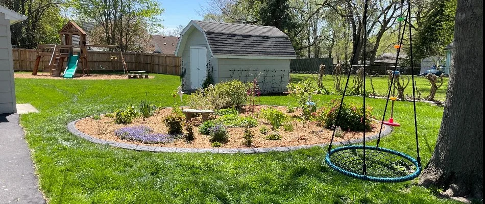 Tidy yard featuring a landscape bed and play area in Urbandale, IA.