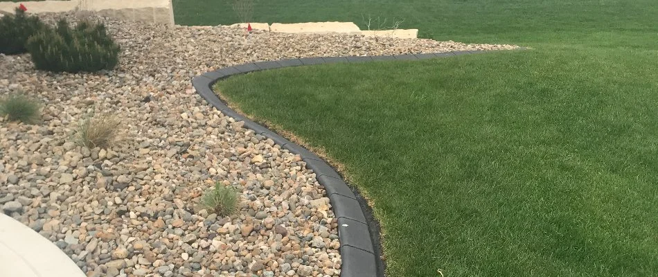 Green lawn beside landscape bed with rocks and shrubs in Des Moines, IA.