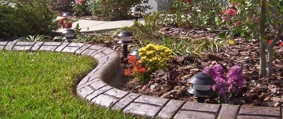 Landscape bed in Booneville, IA, with mulch, flowers, and concrete edging.