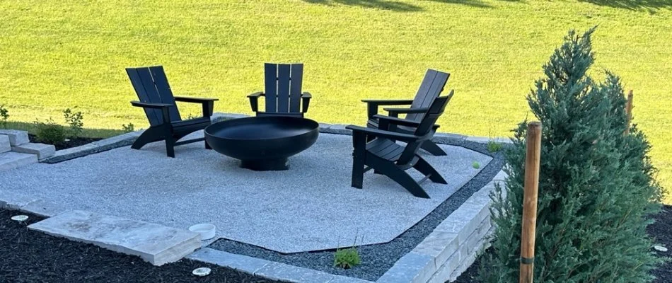 Patio with fire pit surrounded by black chairs.