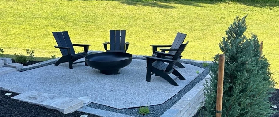 Patio, fire pit, and small shrub by a green lawn in Des Moines, IA.