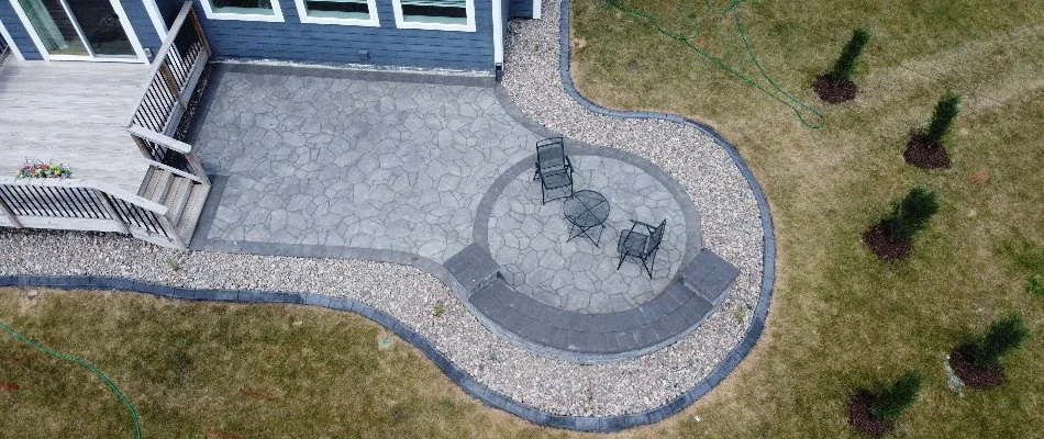 Round patio in Cumming, IA, with landscaping rocks and green lawn.