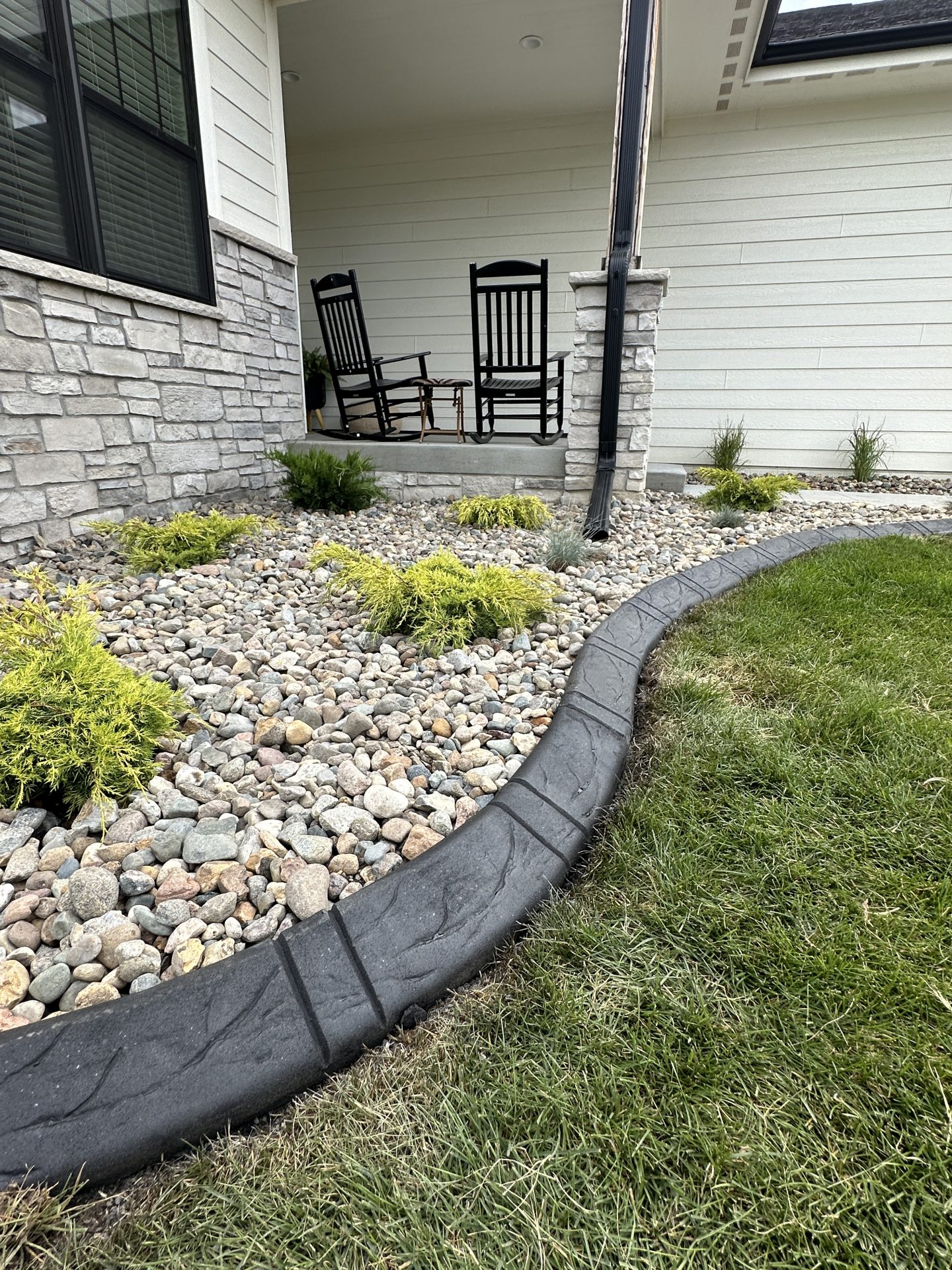 A smooth gravel garden bed with a downspout.
