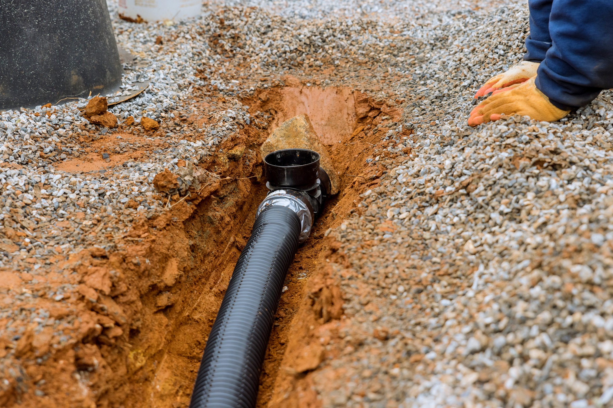 Putting the drainage pipe for rain water on the gravel sidewalk of the car parking lot where the parking lot is covered with gravel